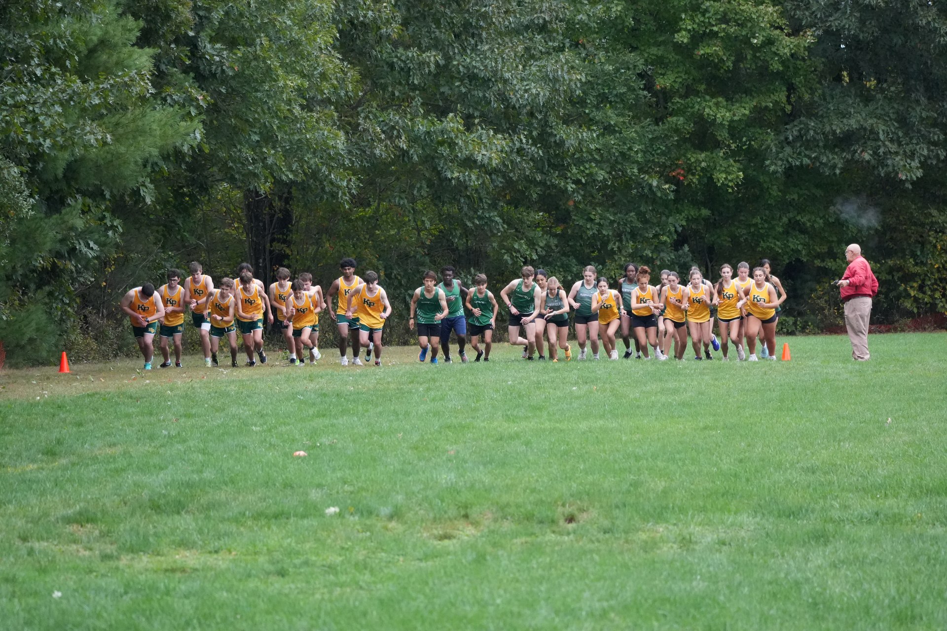 The shared JV starting line, with both teams spread across the grass.
