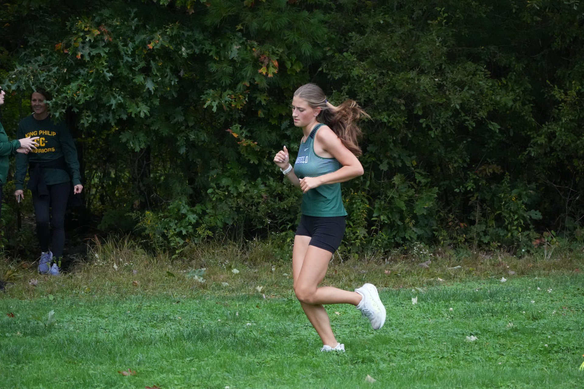 A runner coming along the edge of the trees.